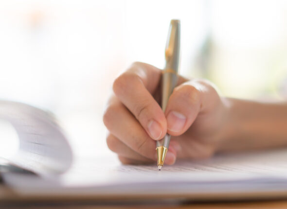 Hand with pen over application form
