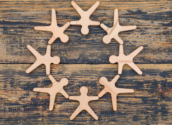 Marketing concept with wooden figures of person stand in circle on wooden background flat lay.